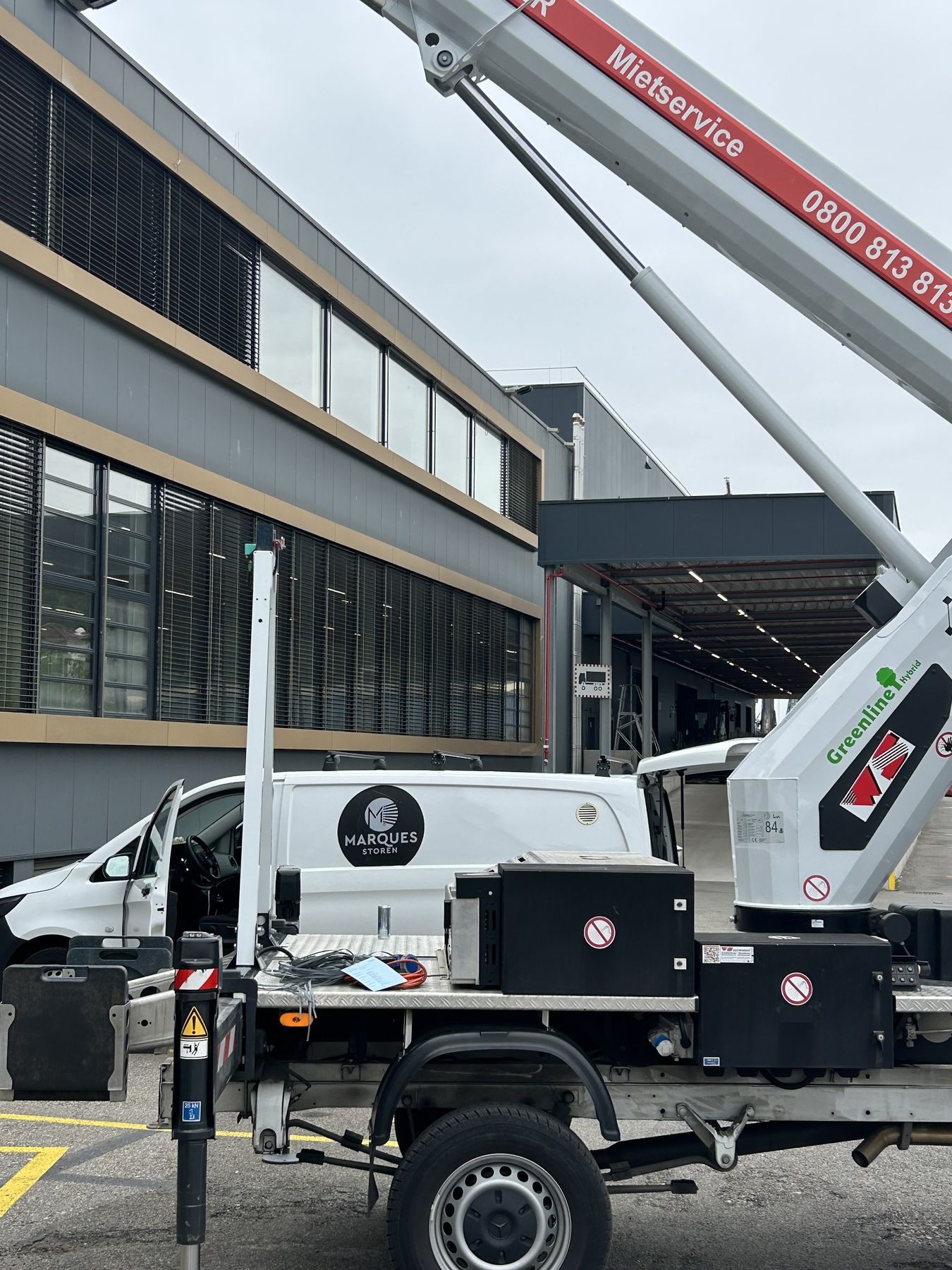 Firmenfahrzeug von Marques Storen mit Hebebühne vor einem Gebäude mit Lamellenstoren